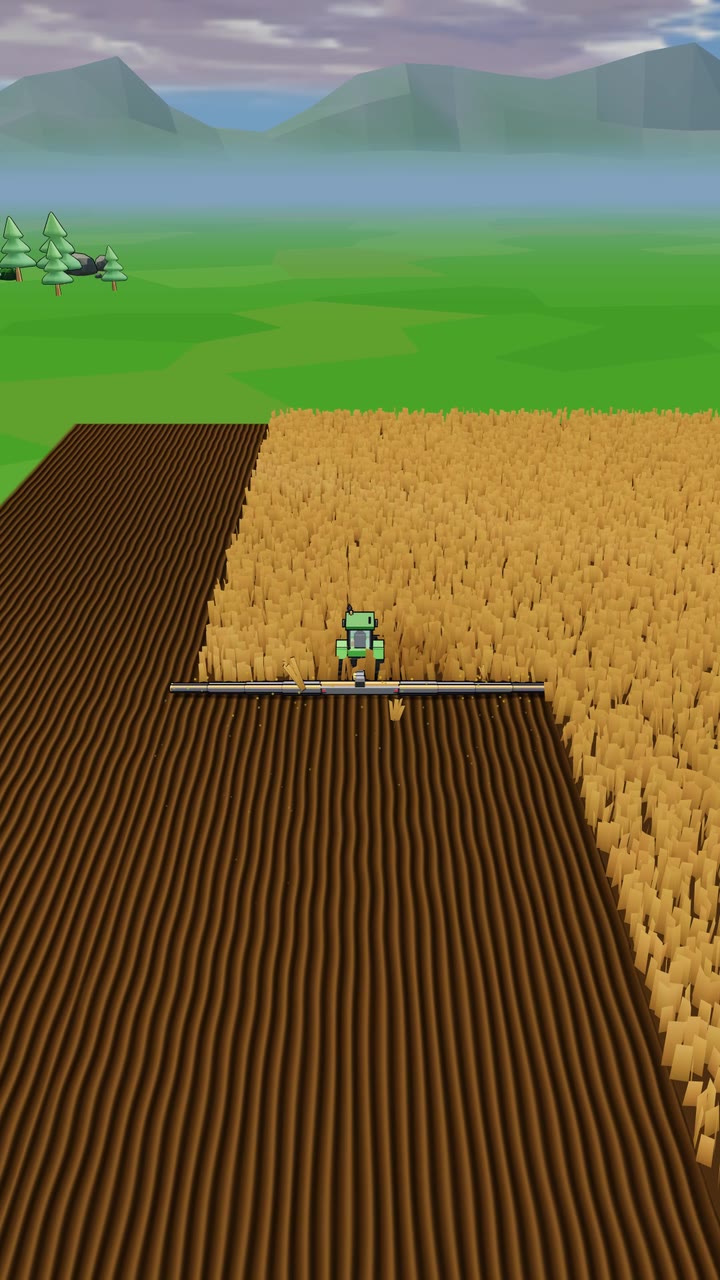 A green tractor cutting a stripe through a golden field, with mountains behind